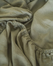Close-up of sage green linen fitted sheet with elastic band